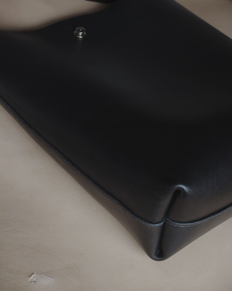 En minimalistisk og funktionel skuldertaske i sort kernelæder, designet til både hverdag og arbejde. Tasken rummer ét stort hovedrum med god plads til de ting, du har brug for – uanset om det er computer, dokumenter eller personlige ejendele. De brede stropper, monteret med solide nitter, gør den behagelig at bære over skulderen, og læderet vil med tiden udvikle en smuk patina, som gør hver taske unik. En enkel og tidløs taske, der kombinerer æstetik med holdbarhed – skabt til at følge dig i mange år fremover.